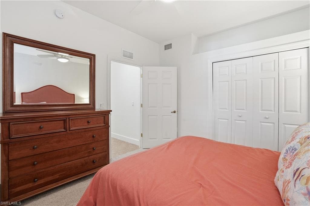 Bedroom featuring light colored carpet, a closet, and a ceiling fan