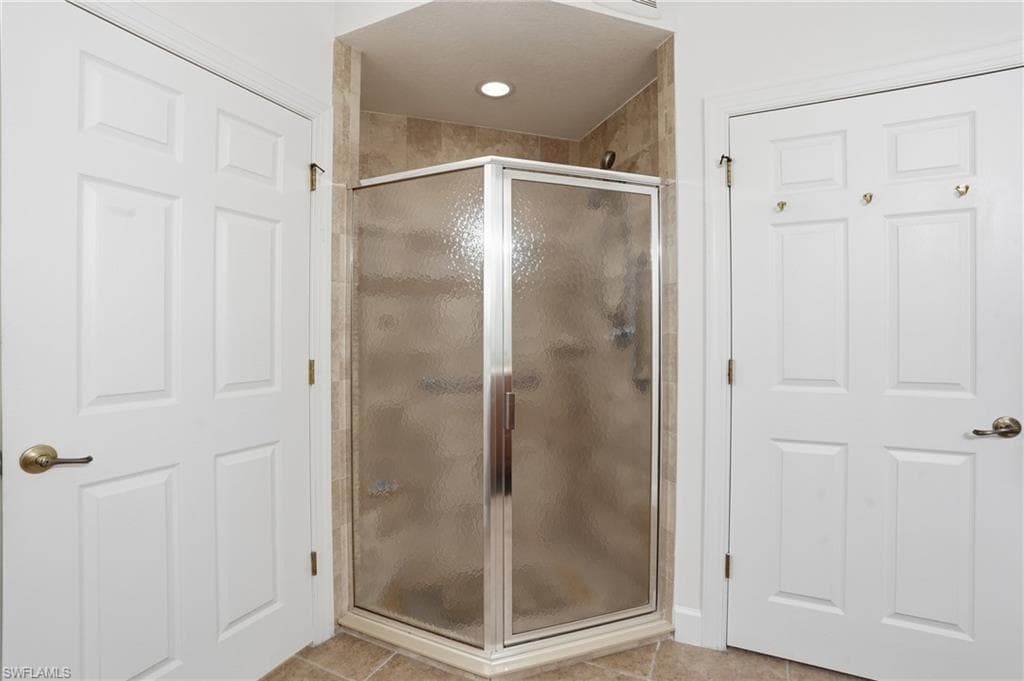 Bathroom featuring a shower stall and light tile patterned floors
