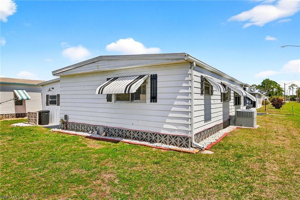 View of property exterior with a lawn and a central AC unit
