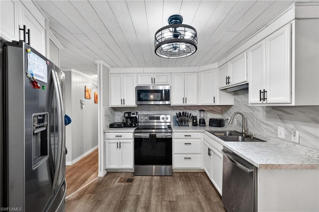 Kitchen featuring stainless steel appliances, light countertops, white cabinetry, and backsplash