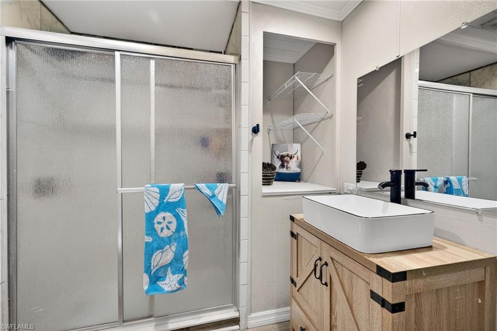 Bathroom featuring vanity, a shower stall, and ornamental molding