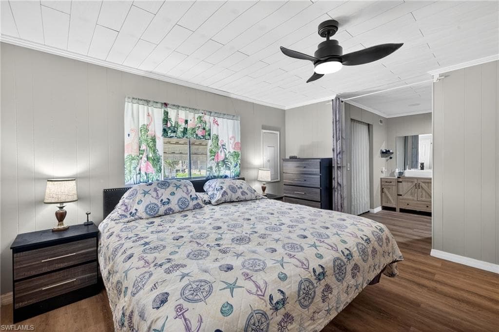 Bedroom featuring dark wood-style flooring, a ceiling fan, wood walls, and ornamental molding