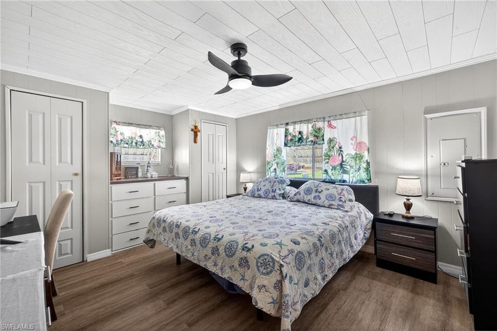 Bedroom featuring wood-type flooring, a ceiling fan, multiple closets, ornamental molding, and wood ceiling