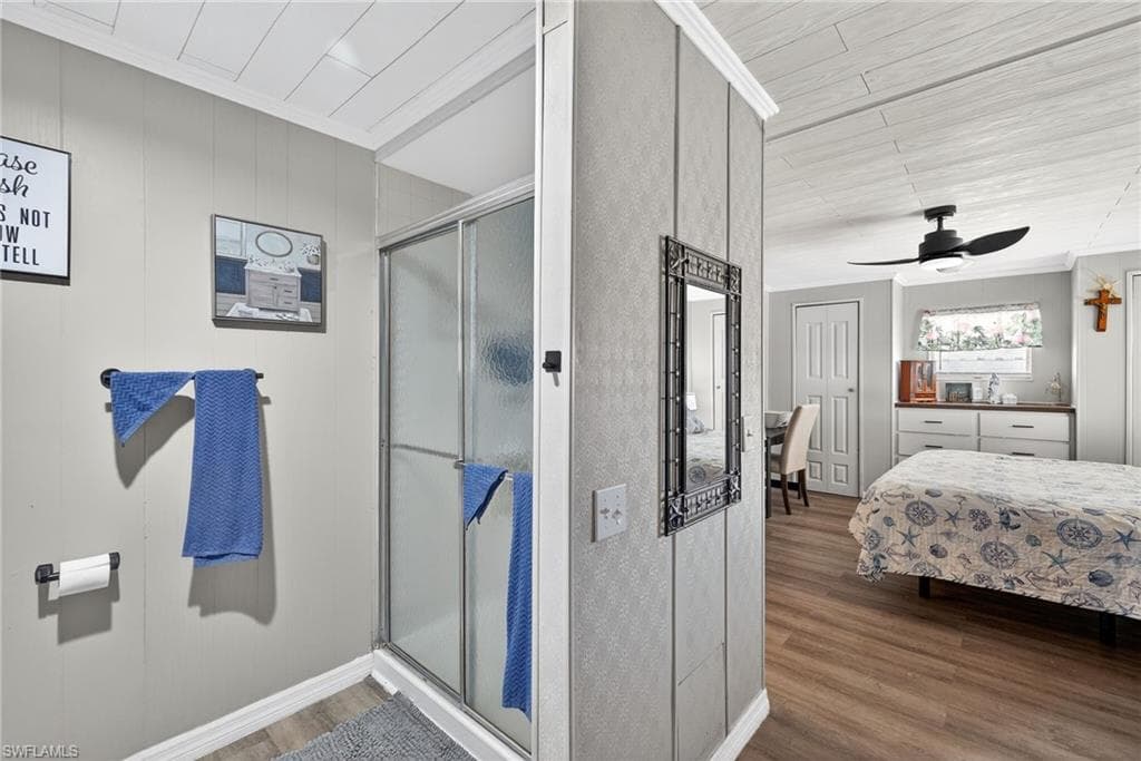 Ensuite bathroom with crown molding, a stall shower, wood finished floors, and a ceiling fan