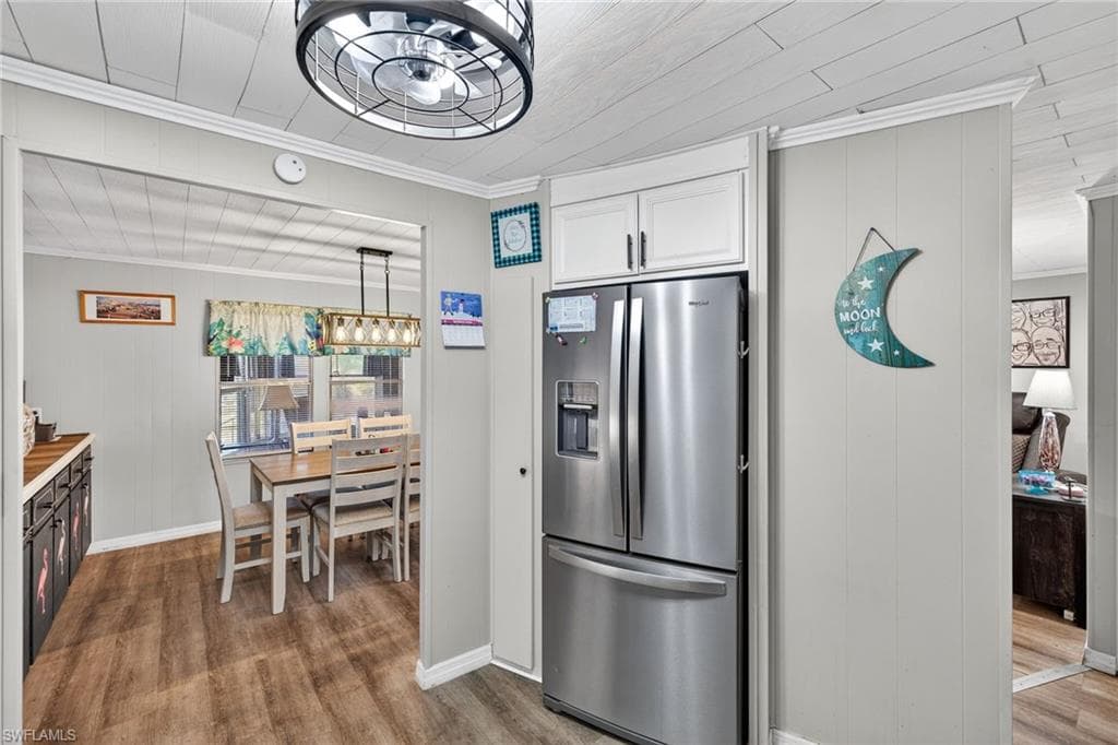 Kitchen featuring stainless steel fridge, crown molding, dark wood-type flooring, and wooden walls