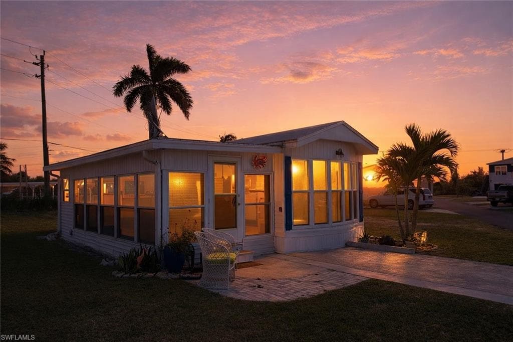 View of front of property with a front yard, a patio area, and a sunroom