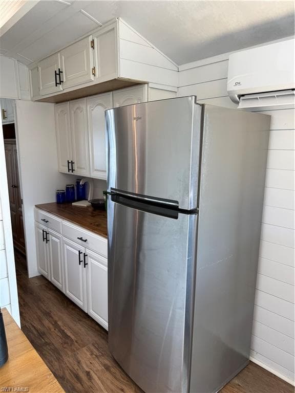 Kitchen with freestanding refrigerator, white cabinets, dark wood-type flooring, and wooden counters