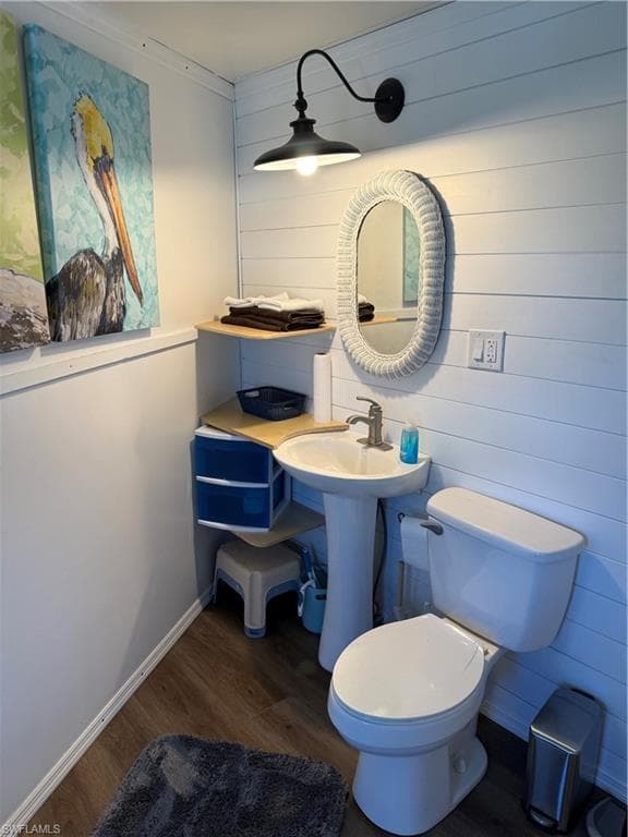 Half bathroom with dark wood-style flooring and wooden walls