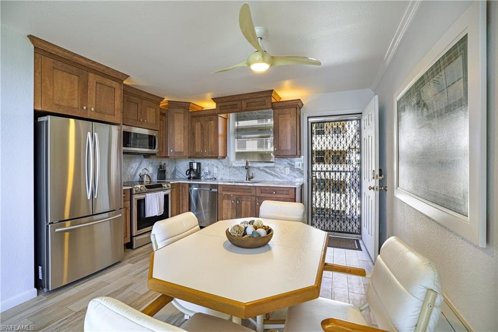 Kitchen featuring stainless steel appliances, a ceiling fan, tasteful backsplash, and light wood-style flooring