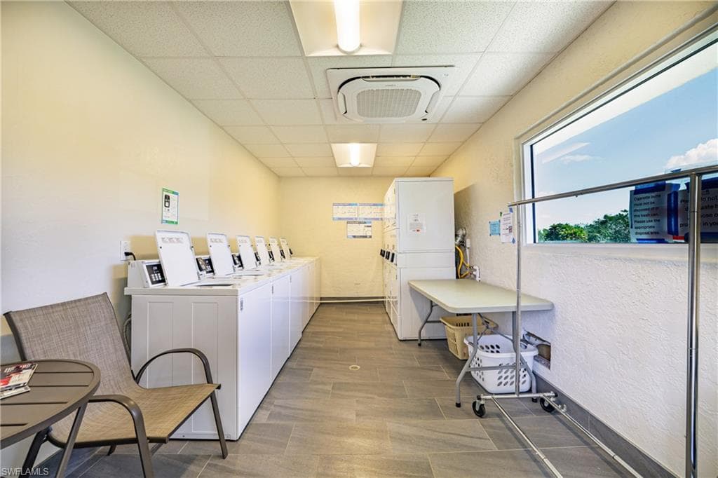 Shared laundry with a drop ceiling, washer and clothes dryer, and a textured wall