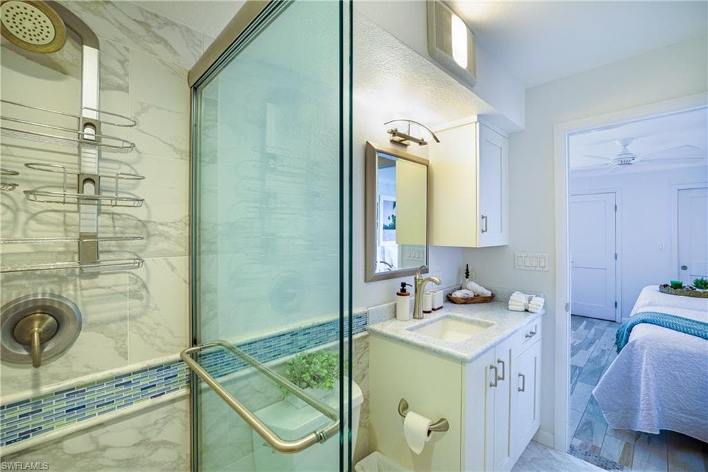 Ensuite bathroom with vanity, a shower stall, and a ceiling fan