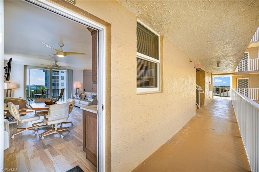 Hallway with a textured wall, a textured ceiling, expansive windows, and light wood-type flooring