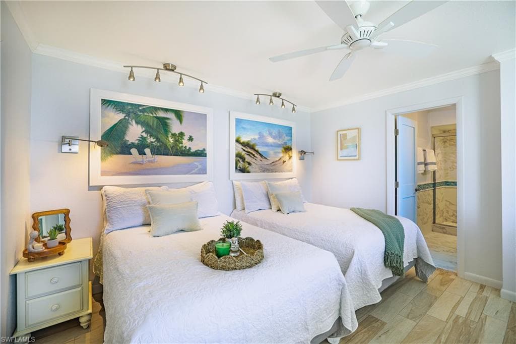 Bedroom with ensuite bathroom, ornamental molding, light wood-type flooring, and ceiling fan