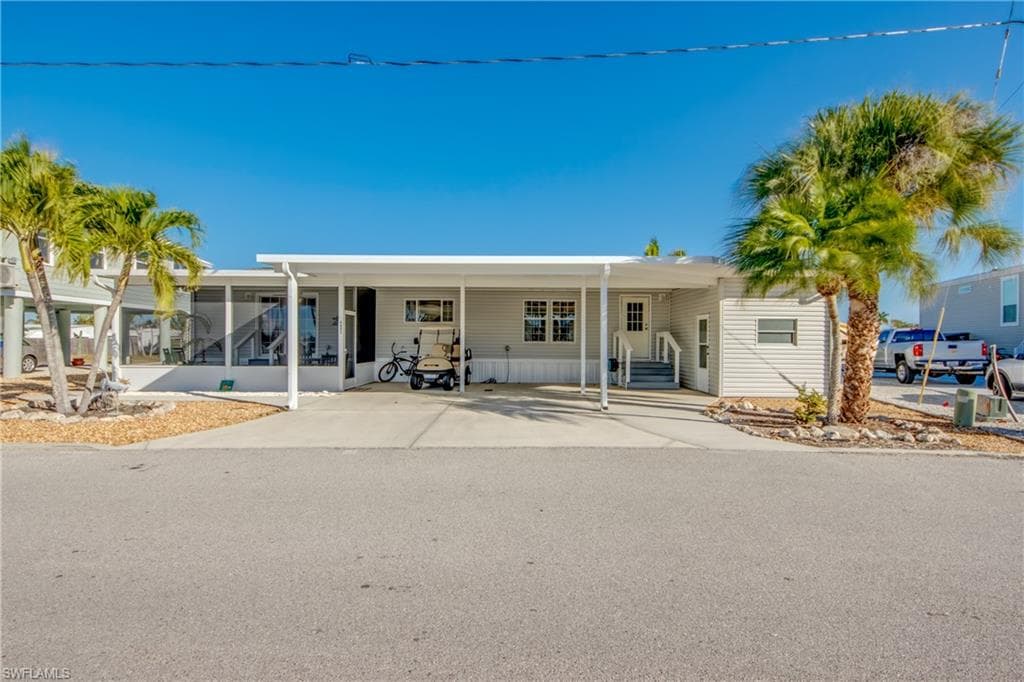 View of front facade with an attached carport and concrete driveway
