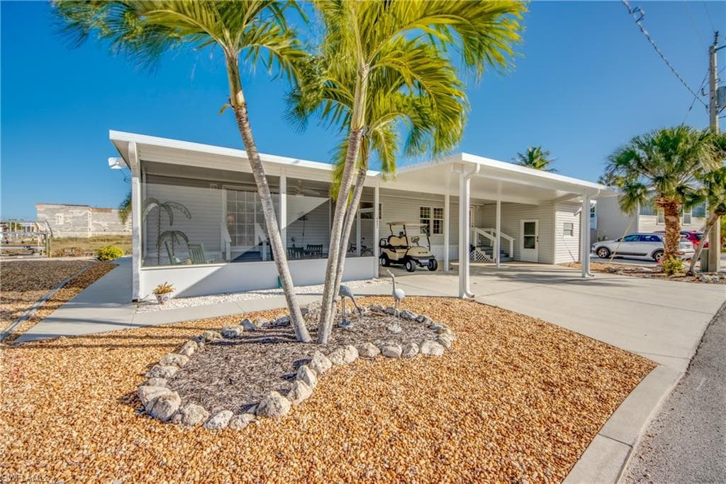 Back of house with an attached carport, concrete driveway, and a sunroom