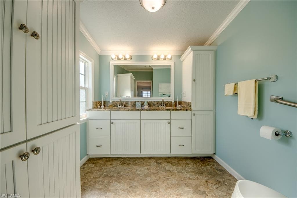 Bathroom featuring ornamental molding, double vanity, and a textured ceiling