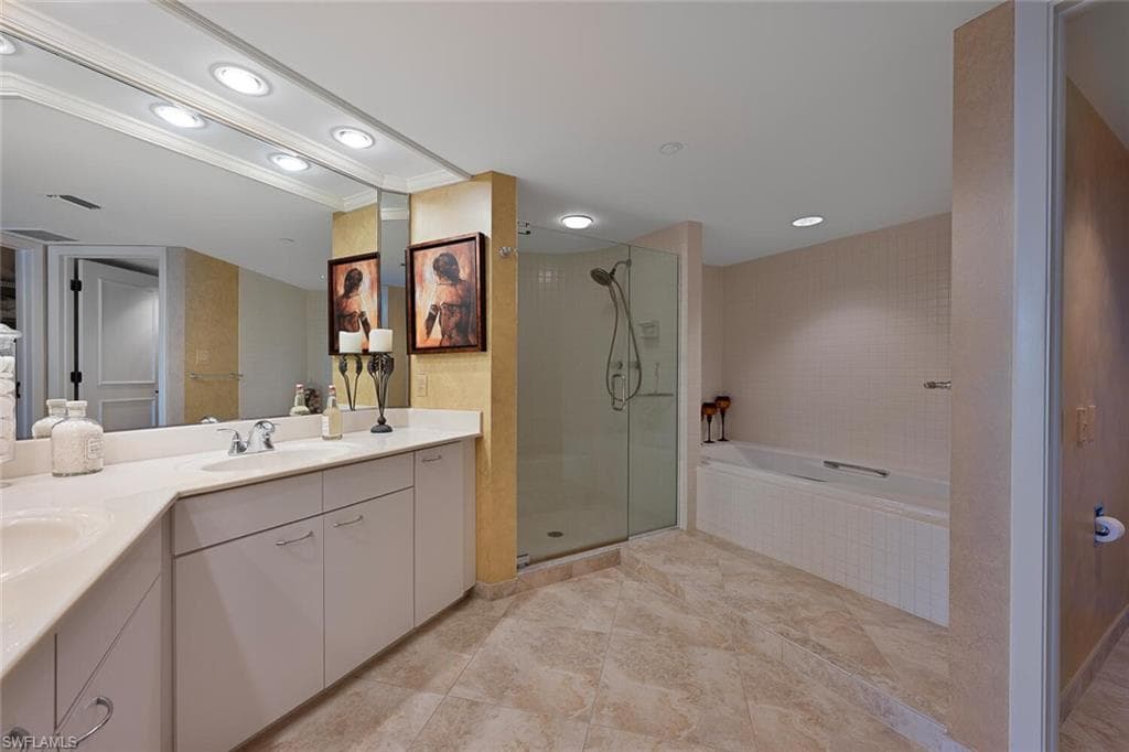 Full bath with double vanity, a garden tub, a stall shower, and recessed lighting