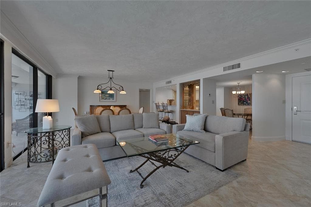 Living area with hanging lights and ornamental molding