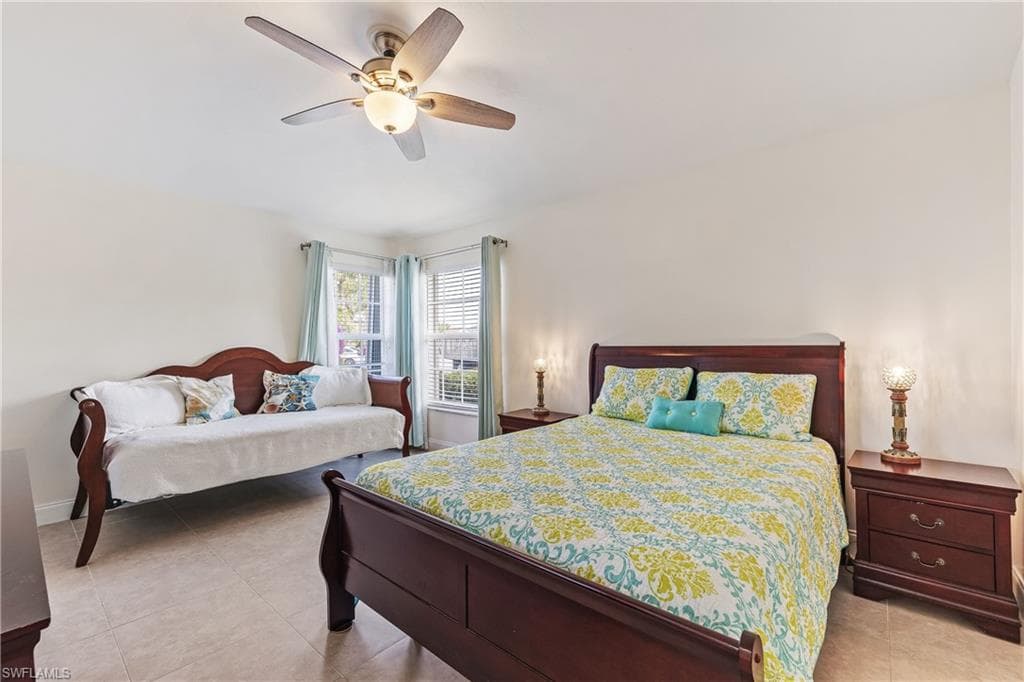 Guest bedroom featuring tiled floor, walk-in closet, and ceiling fan