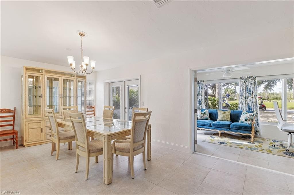 Tiled dining area featuring french doors and ceiling fan with notable chandelier