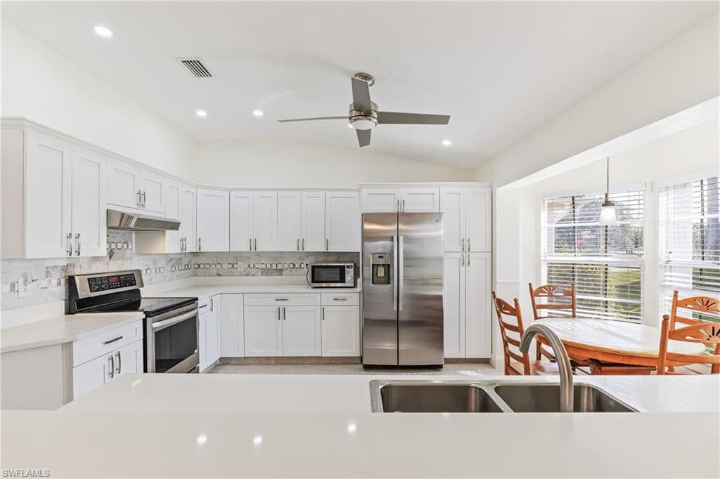 Updated Kitchen featuring sink, white cabinets, appliances with stainless steel finishes, and quartz counters