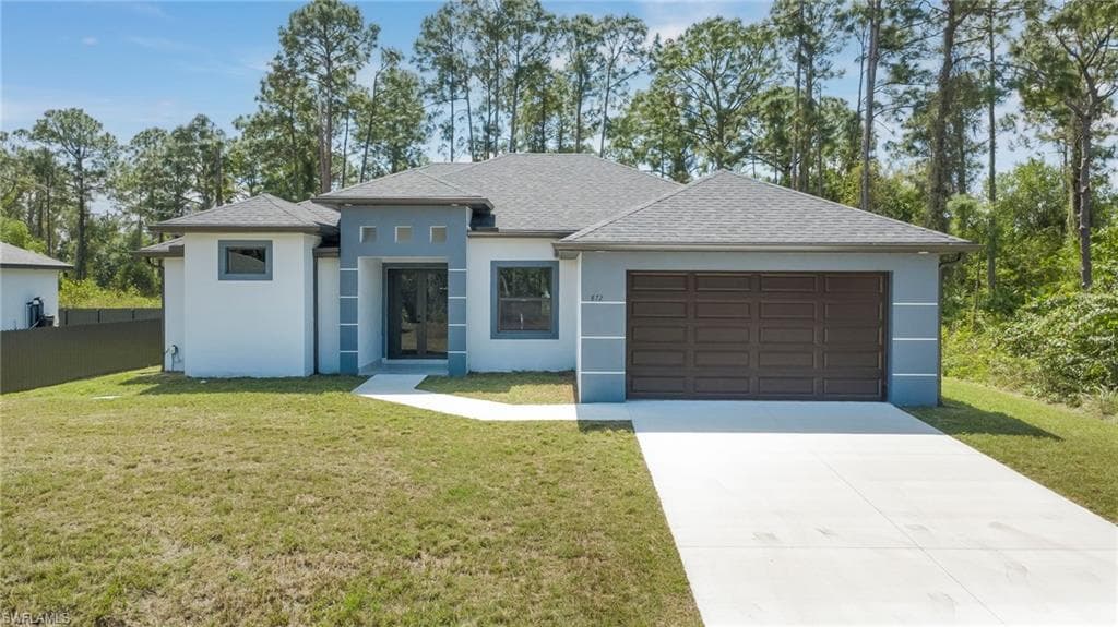 View of front of home featuring a front yard, a shingled roof, an attached garage, and concrete driveway