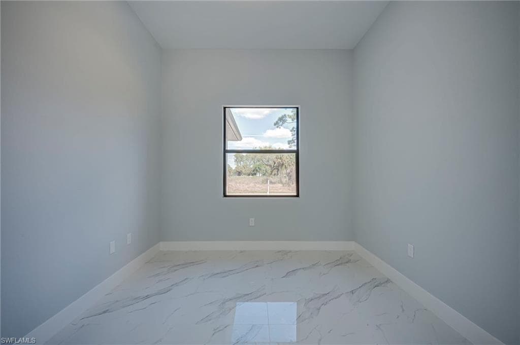 Empty room featuring light marble finish flooring and baseboards
