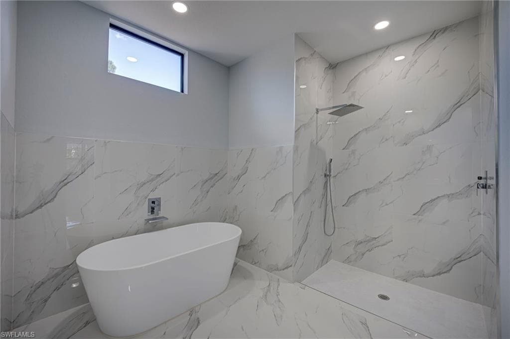Full bathroom with a marble finish shower, recessed lighting, a freestanding bath, tile walls, and marble tiled flooring