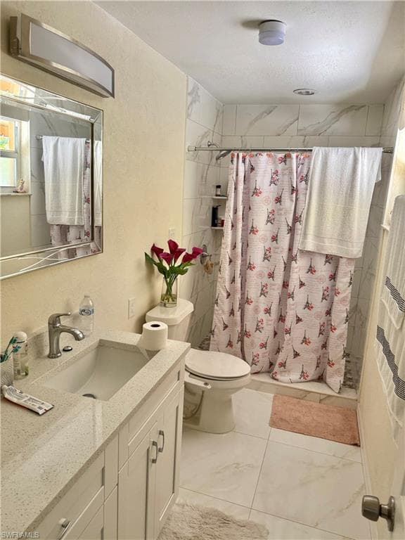 Bathroom featuring vanity, a stall shower, and a textured wall