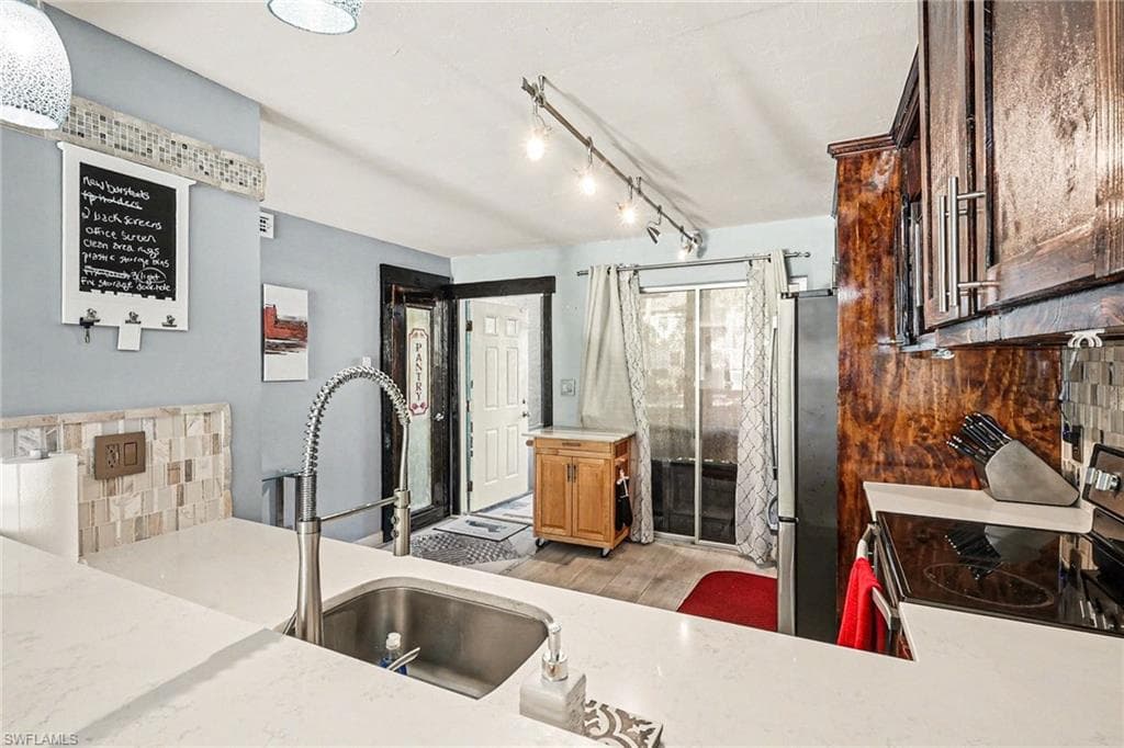 Kitchen with stainless steel appliances, tasteful backsplash, and light stone counters