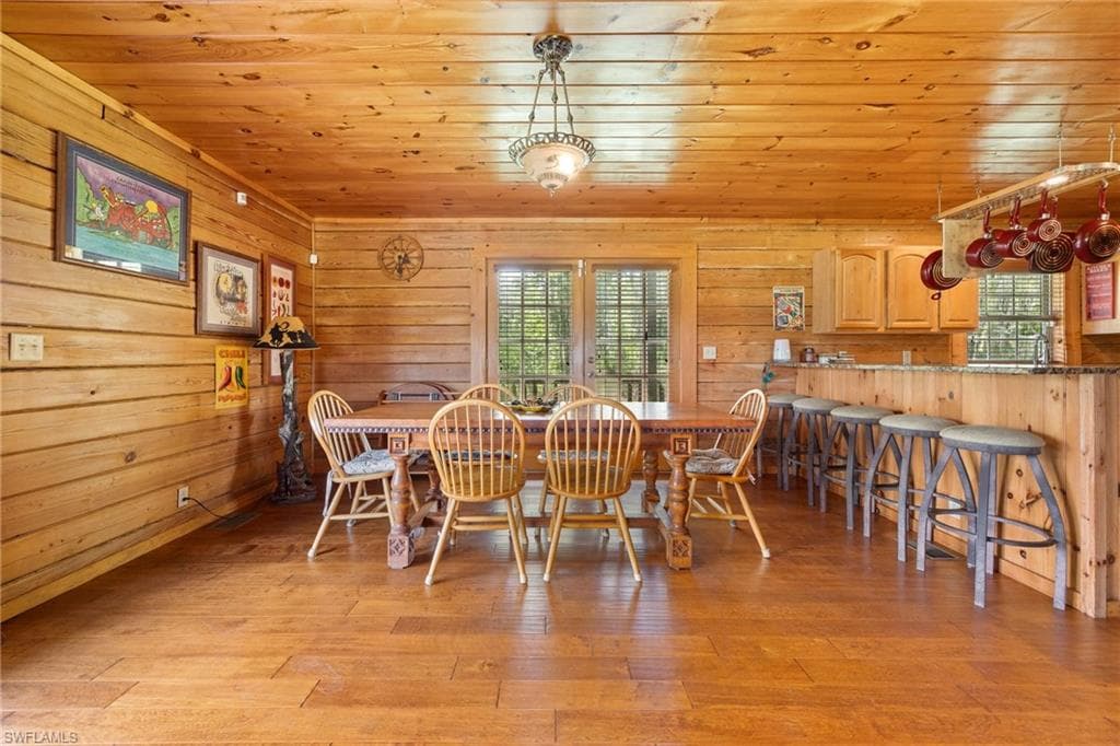 Dining area with wooden walls, wood ceiling, and light wood-type flooring