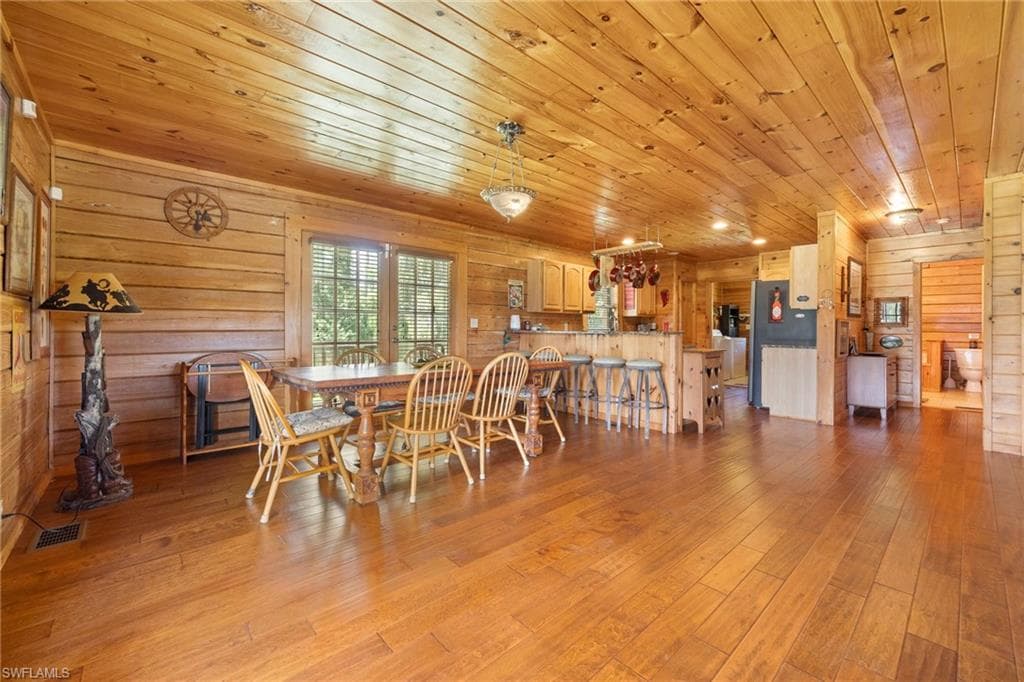 Dining room with wood walls, light wood-style floors, and wooden ceiling
