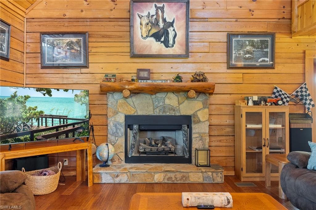 Living area featuring wood walls, wood-type flooring, and a fireplace
