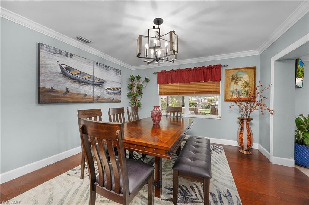 Dining room featuring crown molding, dark wood-style floors, and a chandelier