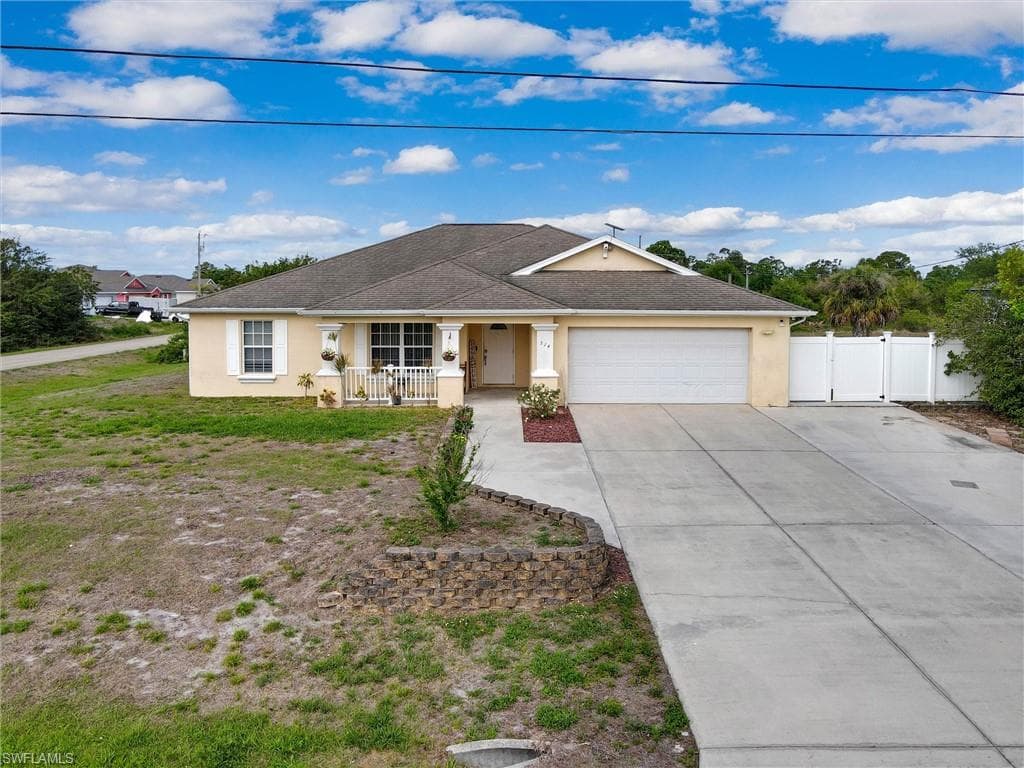 Ranch-style home featuring stucco siding, driveway, an attached garage, covered porch, and a gate