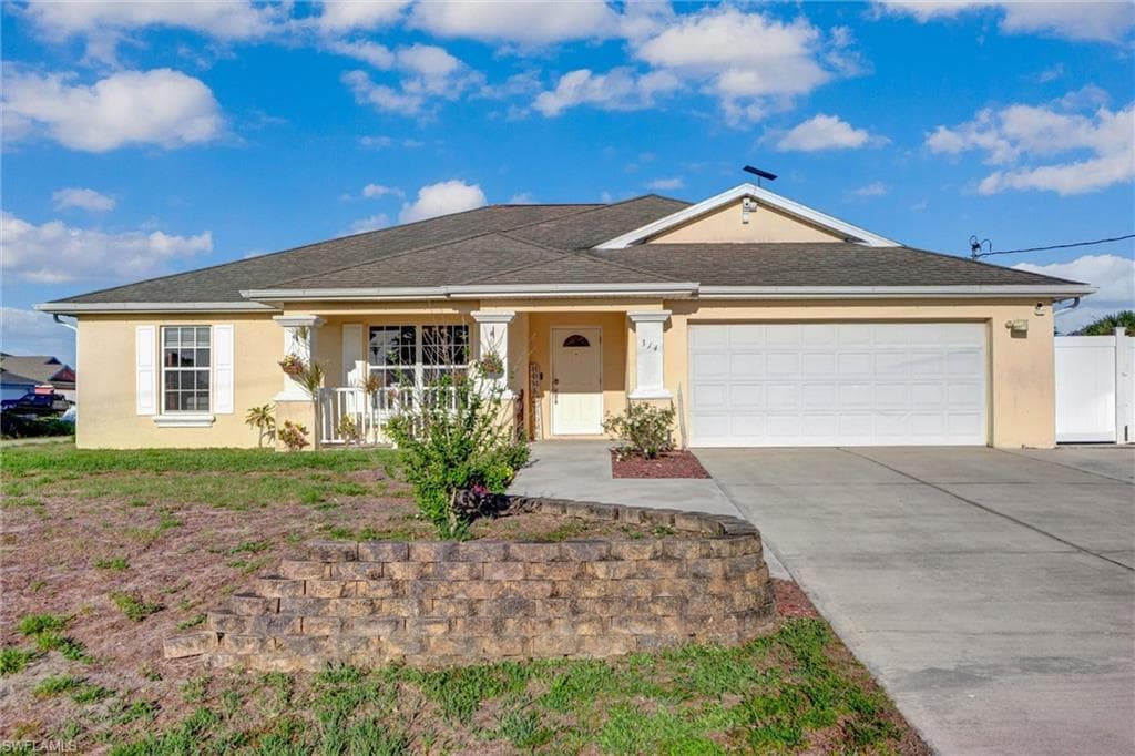 Ranch-style house with covered porch, stucco siding, an attached garage, and driveway