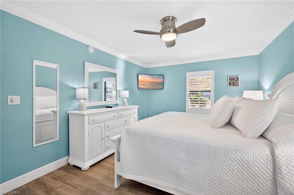 Primary Bedroom featuring light wood-type flooring, multiple windows, crown molding, and ceiling fan