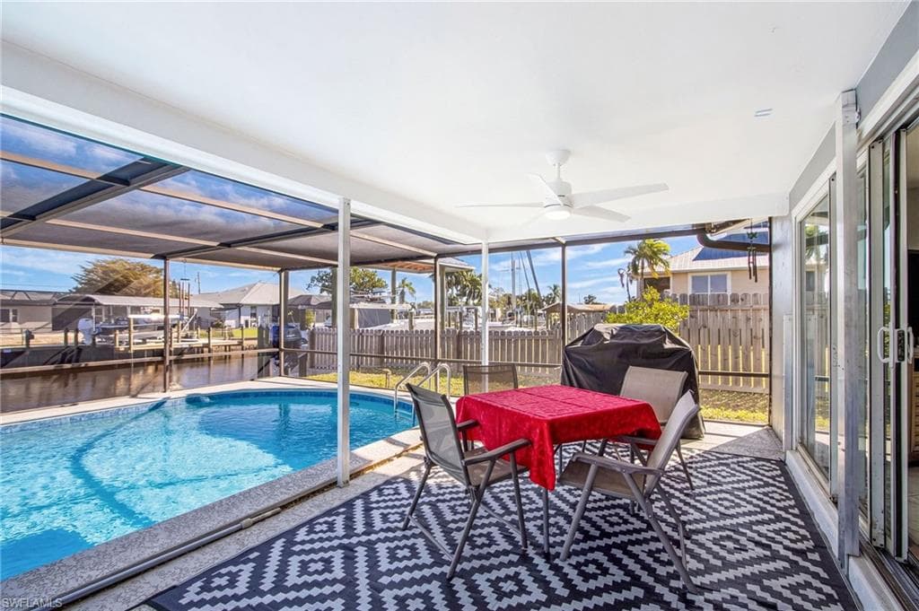 View of swimming pool with glass enclosure, a sunroom, a fenced backyard, outdoor dining area, and a residential view