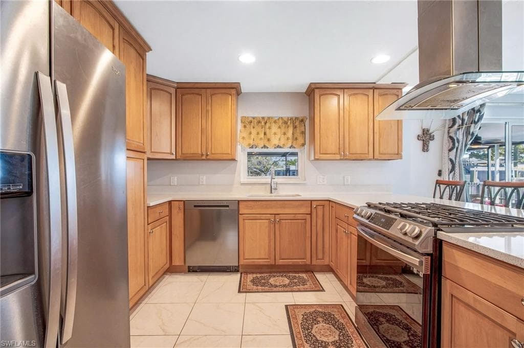 Kitchen featuring stainless steel appliances, island range hood, recessed lighting, light stone counters, and wood finish cabinets