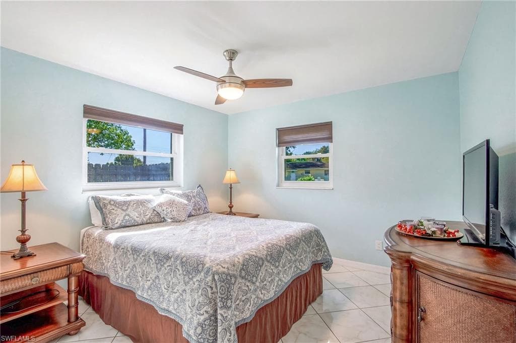 Bedroom with ceiling fan, multiple windows, and light tile patterned flooring