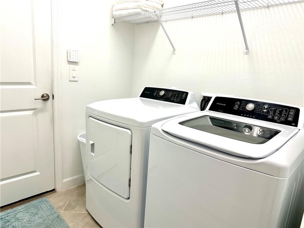 Laundry room featuring light tile patterned floors and washing machine and dryer