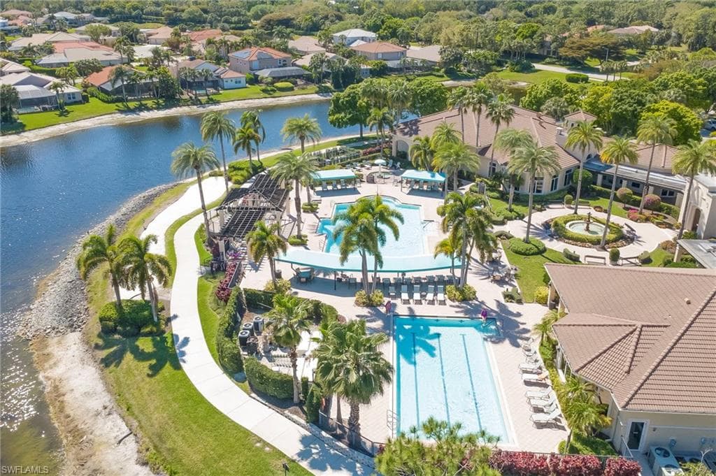 Aerial view of residential area featuring a pool area and a nearby body of water
