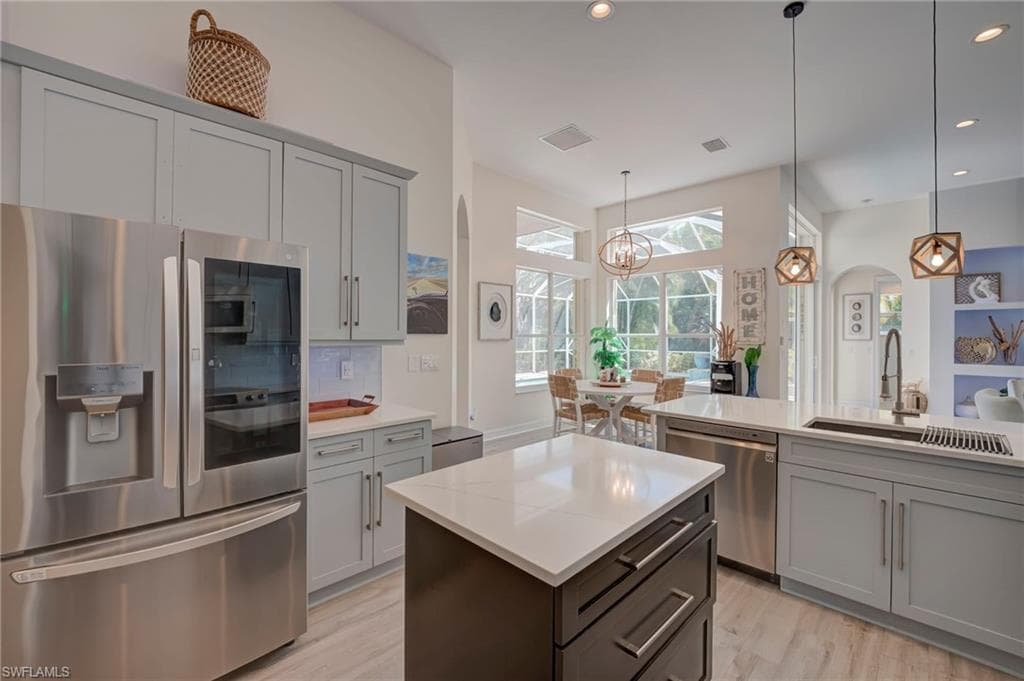 Kitchen with stainless steel appliances, arched walkways, a kitchen island, light wood-style flooring, and gray cabinets