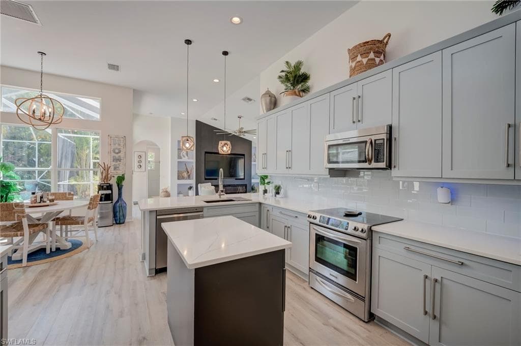Kitchen with stainless steel appliances, a peninsula, decorative backsplash, and light wood finished floors