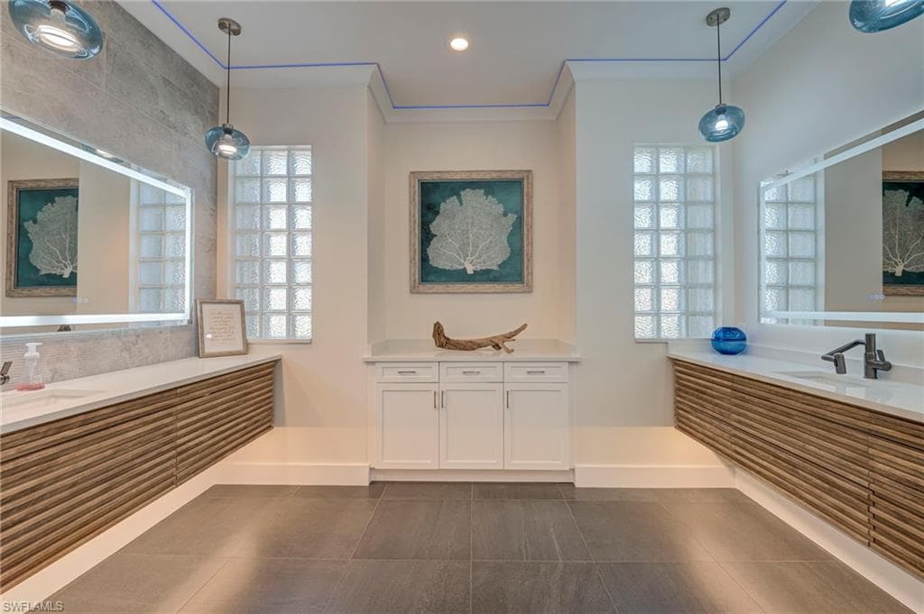 Full bath with two vanities, crown molding, dark tile patterned floors, and recessed lighting