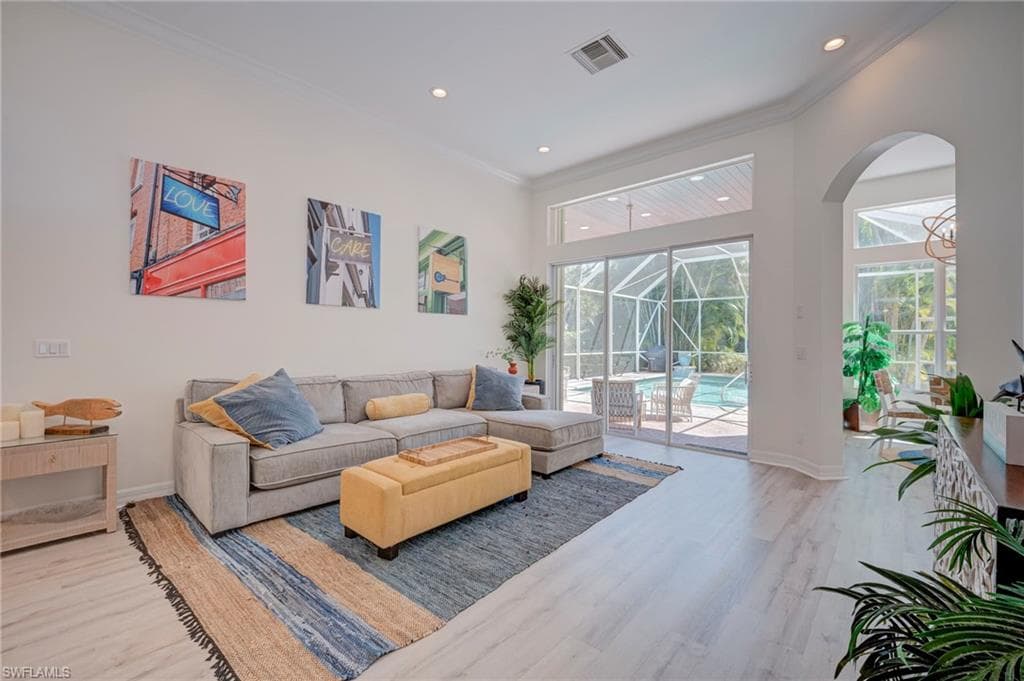 Living room featuring a sunroom, light wood-style floors, crown molding, and recessed lighting