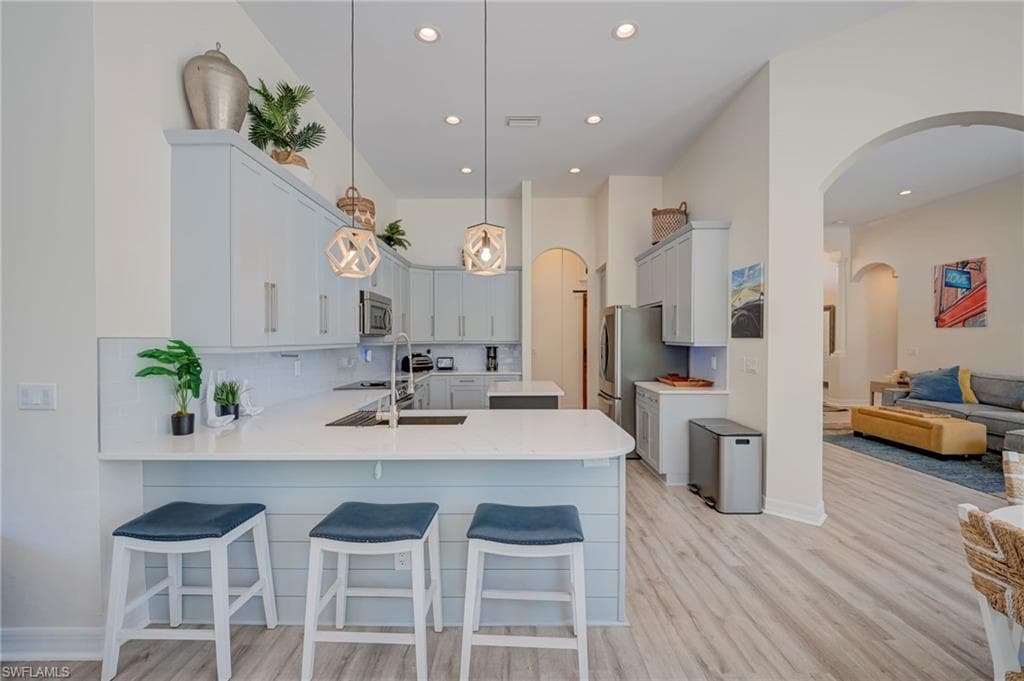 Kitchen featuring arched walkways, a kitchen bar, and light wood finished floors