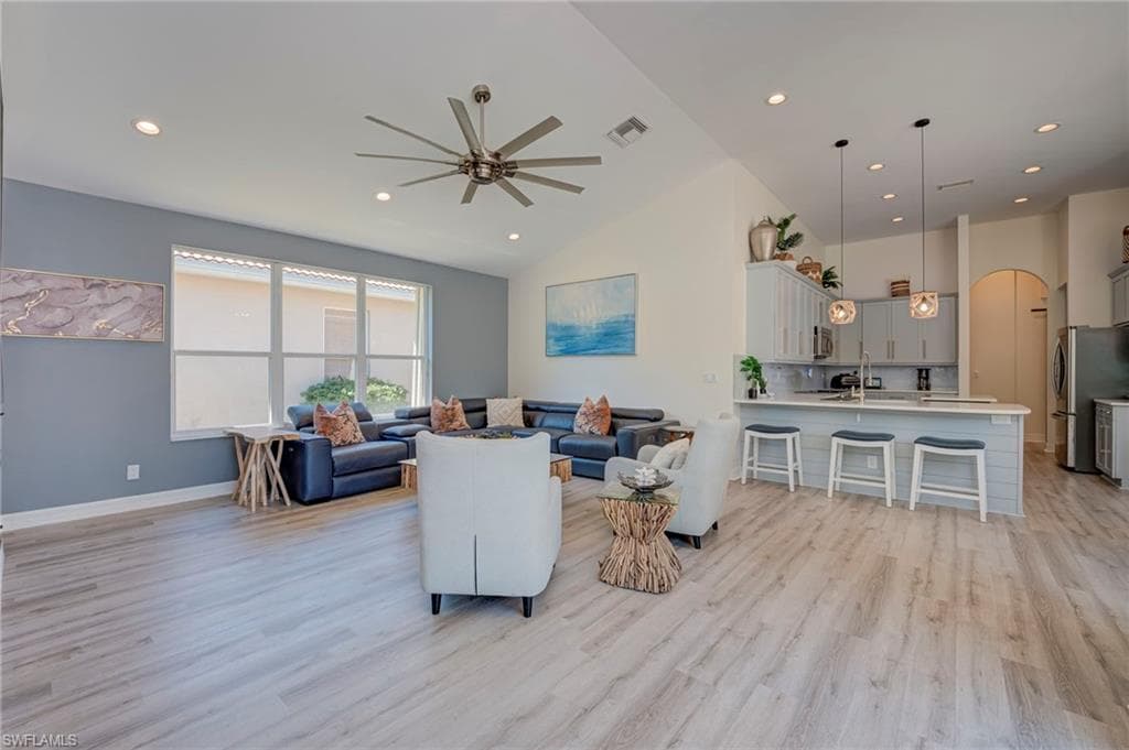 Living room with ceiling fan, recessed lighting, light wood finished floors, arched walkways, and lofted ceiling
