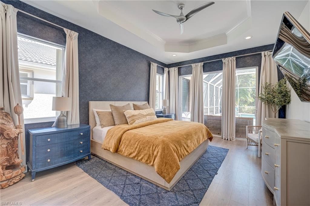 Bedroom featuring access to outside, light wood-style floors, ceiling fan, multiple windows, and ornamental molding