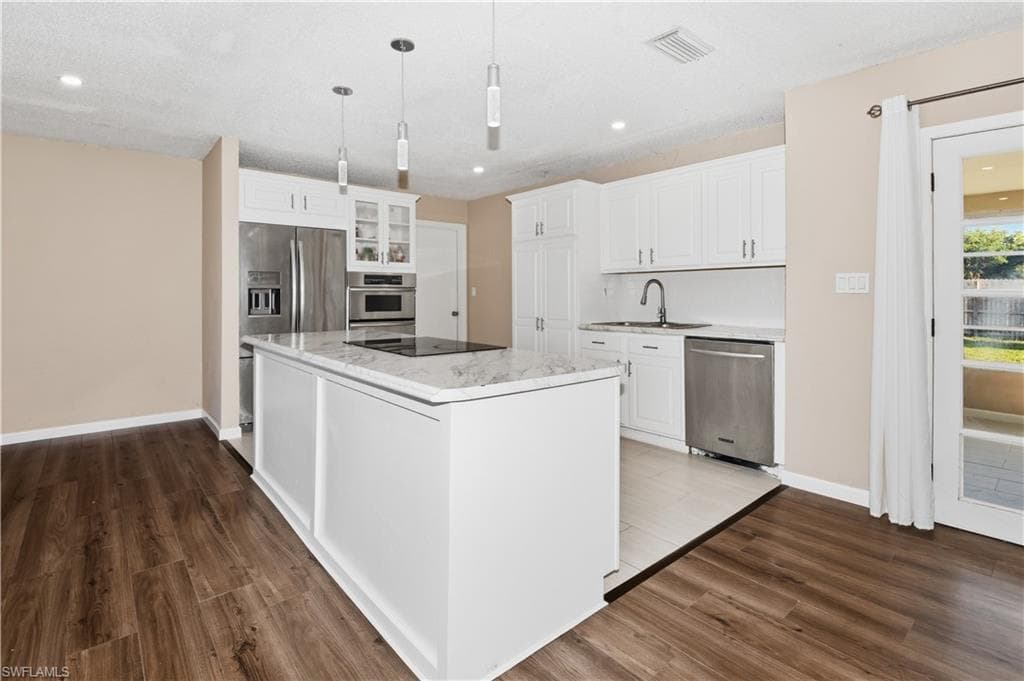 Kitchen featuring white cabinets, dark wood-style flooring, and stainless steel appliances